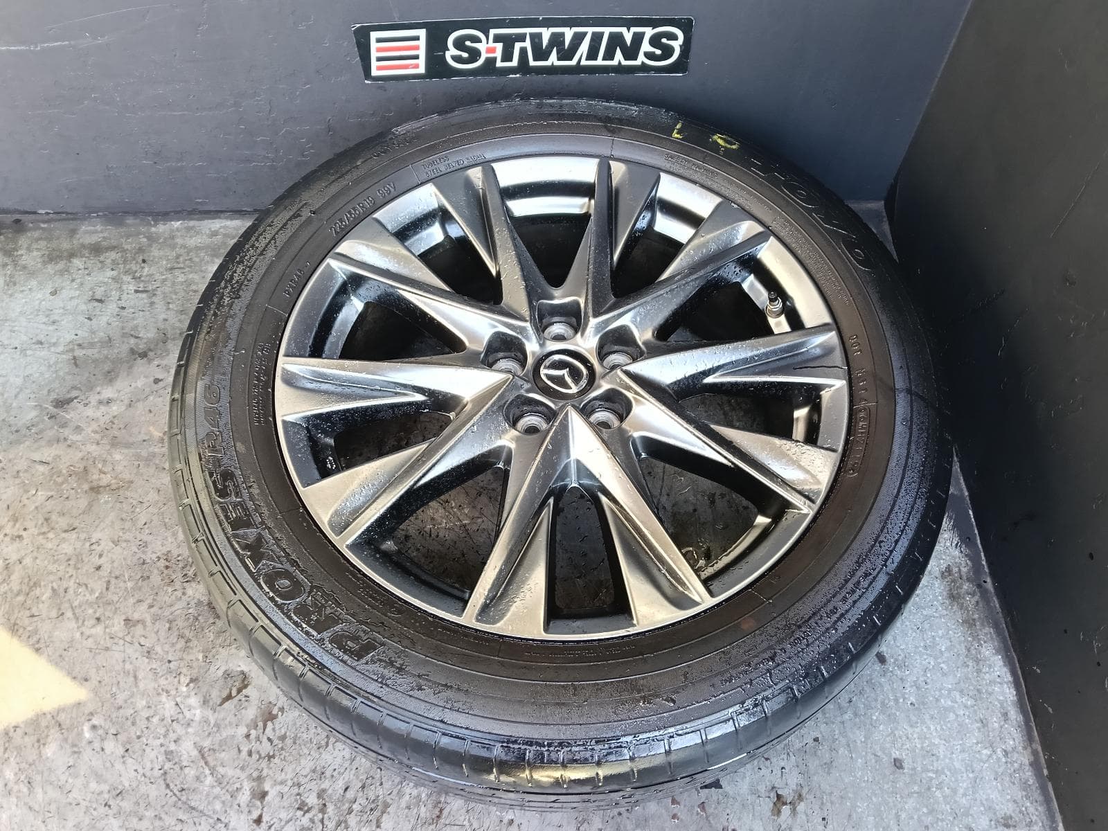Used auto part listing image: 2019 MAZDA CX5 WHEEL MAG FACTORY, 19X7IN, 5 V SPOKE, LIGHT GREY, KF, 05/18-03/26 0000412476